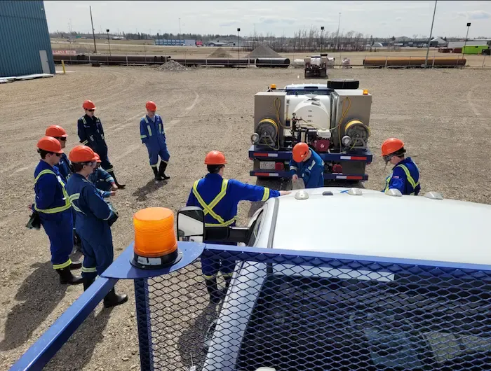Blueweed crew briefing around spray truck at industrial job site